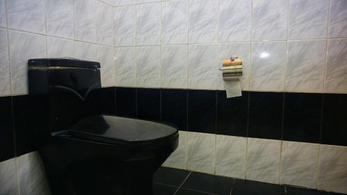 a bathroom with a black toilet and a roll of toilet paper at Dambulla Village Hotel & Restaurant in Dambulla