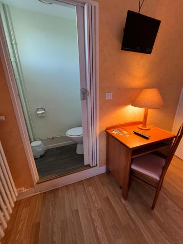 a bathroom with a toilet and a table with a lamp at Aux Quatre Vents in Saulieu