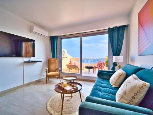 un salon avec un canapé bleu et une grande fenêtre dans l'établissement Magnifique Appartement avec Vue Mer Panoramique, à Nice