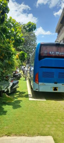 a blue bus parked in the grass next to a building at Surf Gangs Arugambay in Arugam Bay