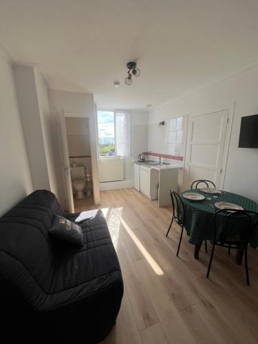 a living room with a black couch and a table at Aux Quatre Vents in Saulieu