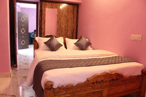 a bedroom with a wooden bed with pink walls at Fort Square Apartments - 201 in Vellore