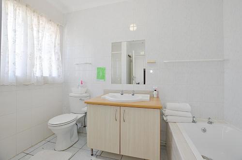a bathroom with a sink and a toilet and a tub at Arum Field Accommodation in Table View