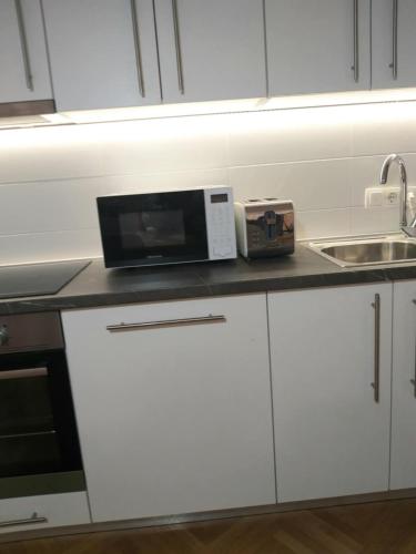 a white kitchen with a microwave and a sink at Alma apartments in Mostar