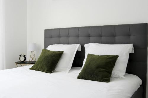 - un lit avec des draps blancs et des oreillers verts dans l'établissement Tage1 - Val d'Europe et Disneyland Paris, à Serris