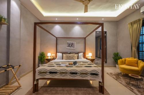 a bedroom with a canopy bed and a yellow chair at EKOSTAY - Noir Villa in Alibaug