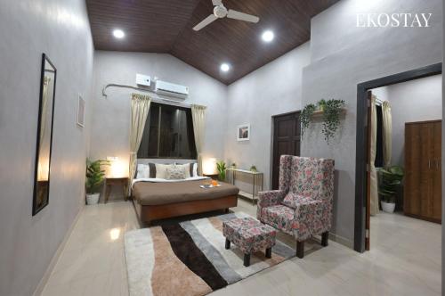 a bedroom with a bed and a chair at EKOSTAY - Noir Villa in Alibaug