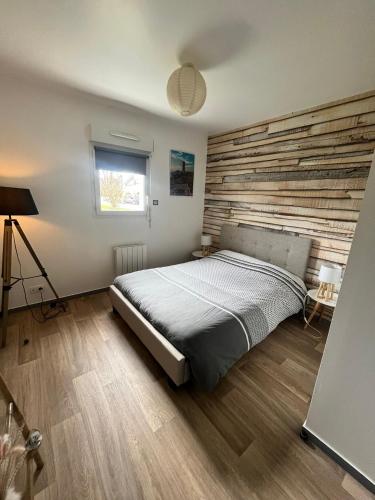 une chambre avec un lit et un mur en bois dans l'établissement Très bel appartement proche de la mer, à Plestin-les-Grèves