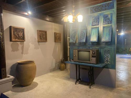 Zimmer mit einem TV auf einem Tisch mit einer Vase in der Unterkunft Dalasone Pool Villa with Stunning Mountain View in Vang Vieng