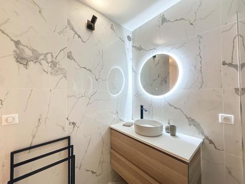 une salle de bain blanche avec un lavabo et un miroir dans l'établissement Élégance et Détente - Parking - Jardin & SPA, à Menton