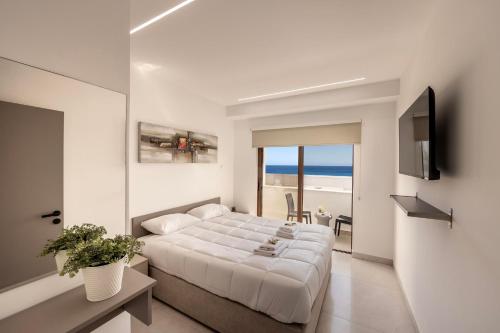 a white bedroom with a bed and a view of the ocean at SEVIS SUITES in Ayia Napa