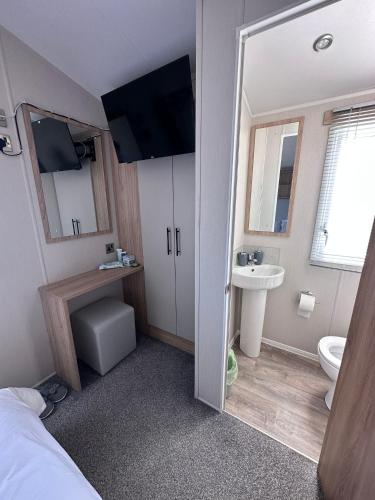 a bathroom with a bed and a sink and a mirror at Selsey Caravan 3 bed in Selsey