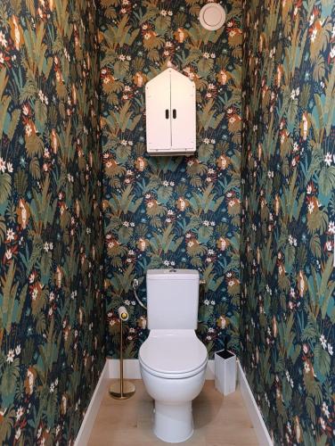 La salle de bains est pourvue de toilettes et de papier peint à fleurs. dans l'établissement Studio coin nuit Riviera Plage, à Roquebrune-Cap-Martin