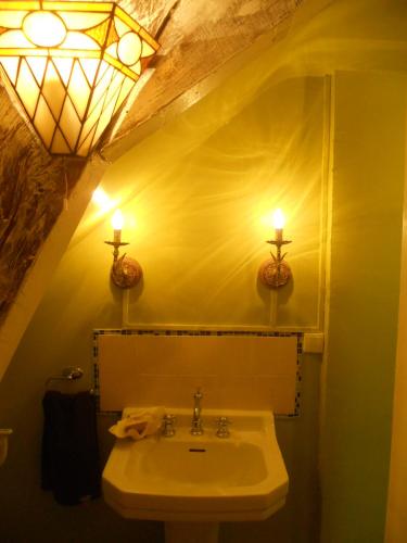 La salle de bains est pourvue d'un lavabo et de deux lumières sur le mur. dans l'établissement Ferme de la Dorvallière, à Cavagnac