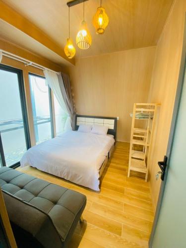 a bedroom with a bed and a couch and windows at Felix's Dalat Homestay in Khu Chi Lăng