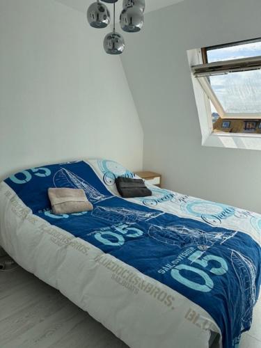 - un lit avec une couette bleue dans l'établissement L'Escapade détente - Appartement 2 à 4 Personnes Villers Sur Mer Proche Plage, à Villers-sur-Mer