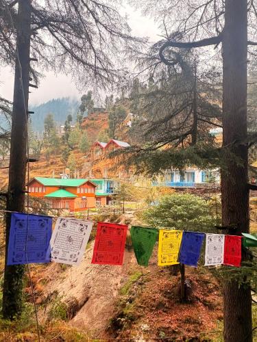 a group of prayer flags hanging in a forest at Pine Nest cottages in Jibhi