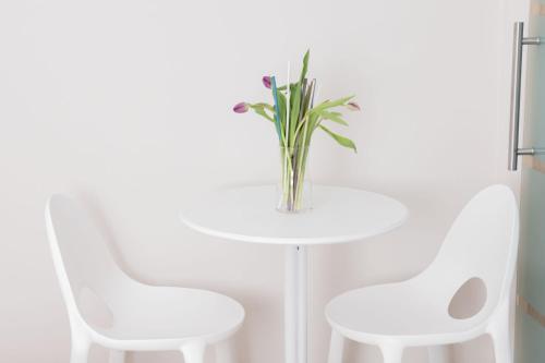 a white table with two chairs and a vase with flowers at B&B Sibi in Chieti