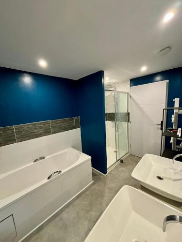 La salle de bains est pourvue d'une baignoire blanche et d'un mur bleu. dans l'établissement Maison Provençale, Piscine, Soleil, Barbecue et Pétanque, à Saint-Gervasy