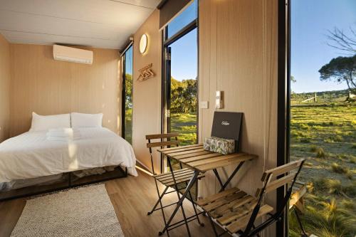 a bedroom with a bed and a desk and a window at Rowsley Valley Tiny House 2 by Tiny Away in Ingliston