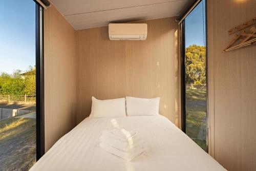 a bed in a room with a large window at Rowsley Valley Tiny House 2 by Tiny Away in Ingliston