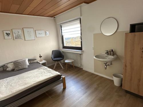 a bedroom with a bed and a sink and a mirror at Gästehaus Heimatliebe in Heimbach