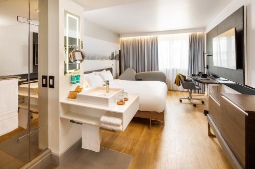 a hotel room with a white bed and a sink at Novotel London Bridge in London