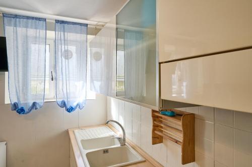 a white bathroom with a sink and a window at Il Giglio in San Vincenzo