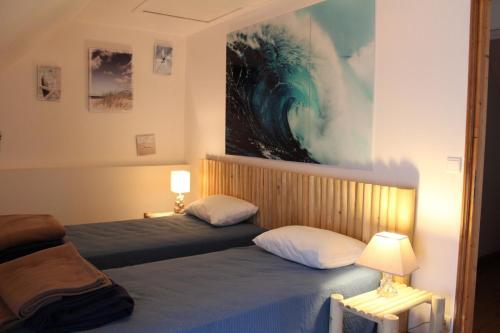 une chambre avec deux lits et un tableau au mur dans l'établissement La Longère de Quily en Brocéliande 12 couchages bain nordique, à Villeder