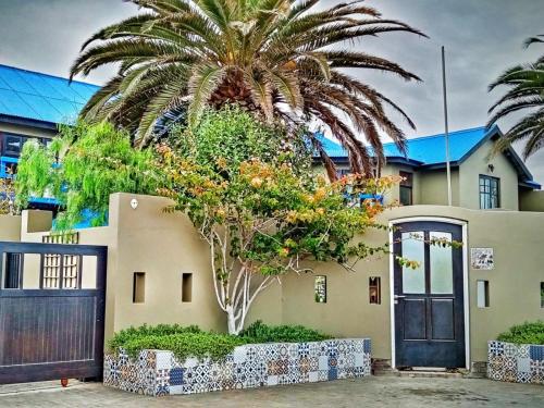 a palm tree in front of a house with a door at 22 on Main Guesthouse Walvis Bay in Walvis Bay
