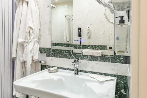 a white bathroom with a sink and a mirror at La Paloma Blanca Hotel in Sciacca