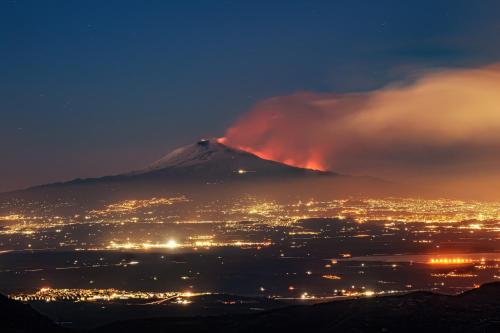 a mountain with a fire in the background at night at Dea's Rooms in Noto