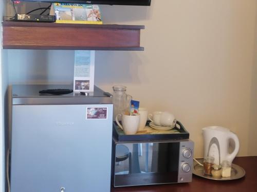 a small kitchen with a microwave and a refrigerator at 22 on Main Guesthouse Walvis Bay in Walvis Bay