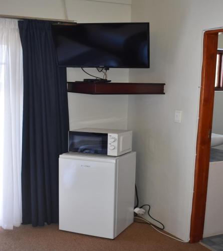 a tv sitting on top of a refrigerator in a room at 22 on Main Guesthouse Walvis Bay in Walvis Bay
