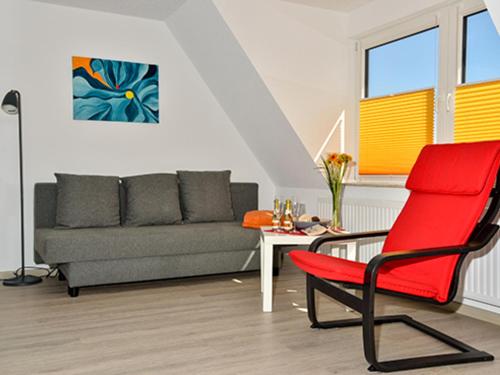 sala de estar con silla roja y sofá en Haus der Gemütlichkeit, en Ribnitz-Damgarten