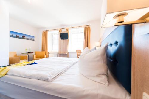 a bedroom with a large white bed with a blue headboard at Hotel Boddenhus Garni in Zingst