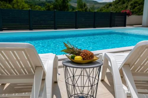 a bowl of fruit on a table next to two chairs at Villas Magnolia in Blagaj