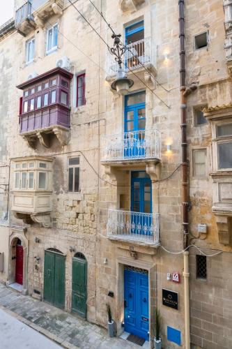 an old building with blue doors and a balcony at Mandera's Boutique Suites & Dorms in Valletta