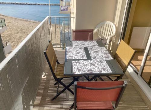 une table et des chaises sur un balcon avec la plage dans l'établissement Le Marco polo appartement T3 les pieds dans l 'eau et garage, au Grau-du-Roi