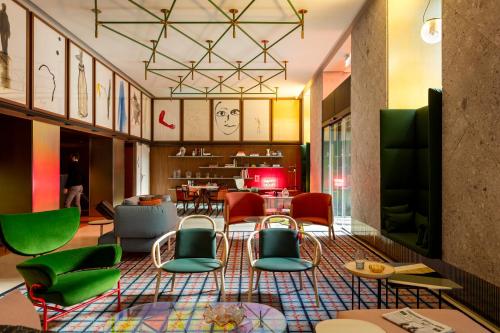a lobby with colorful chairs and a restaurant at Room Mate Giulia in Milan