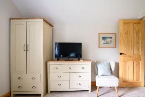 a bedroom with a dresser with a tv and a cabinet at Pass the Keys Fourshires Lodge Wonderful panoramic views in Moreton in Marsh