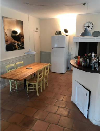 une cuisine avec une table en bois et un réfrigérateur blanc dans l'établissement Le Jardinet vacances dans un coin de paradis au bord de la mer, à Peyriac-de-Mer
