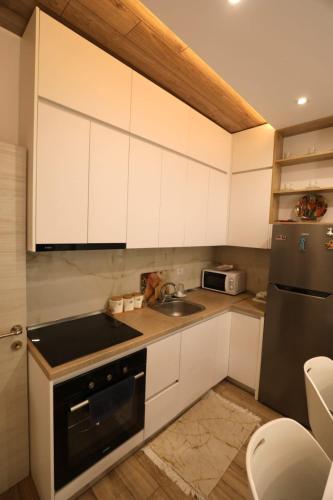 a kitchen with white cabinets and a sink and a refrigerator at Elio Apartament in Pogradec