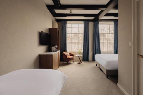 a hotel room with two beds and a window at Adam's Canal House in Amsterdam