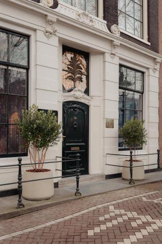 a black door on a white building with two potted plants at Adam's Canal House in Amsterdam