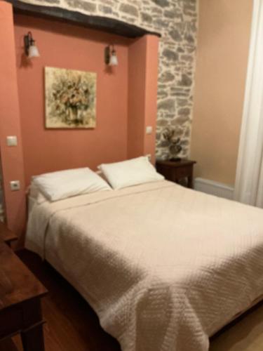 a bedroom with a white bed with a stone wall at Αρχοντικό Πρεπάλα in Neochori