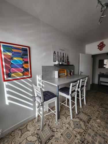 une table de salle à manger avec des chaises et un tableau au mur dans l'établissement Appartement Quai Ouest, vue entrée port, Stationnement gratuit, Lits faits pour votre arrivée, serviettes de toilettes fournies, à Dieppe
