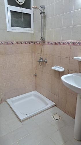 Muscat Women's dormitory في مسقط: حمام مزود بدش ومغسلة