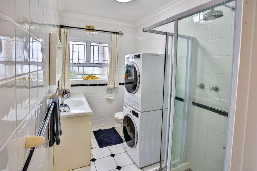 Un baño con lavadora y secadora junto a una ducha. en Villa Bel Fiori Apartment - 4 Sleeper, en Ballito