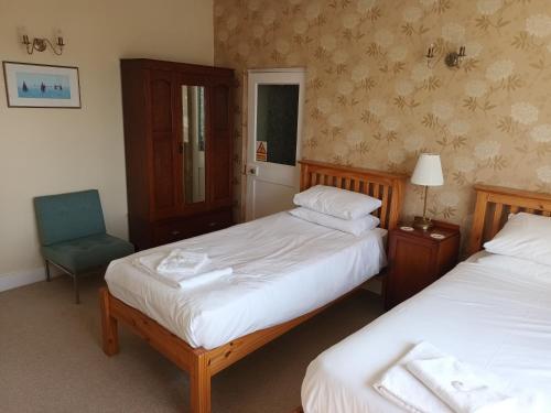 a bedroom with two beds and a chair and a window at Royal Norfolk & Suffolk Yacht Club in Lowestoft
